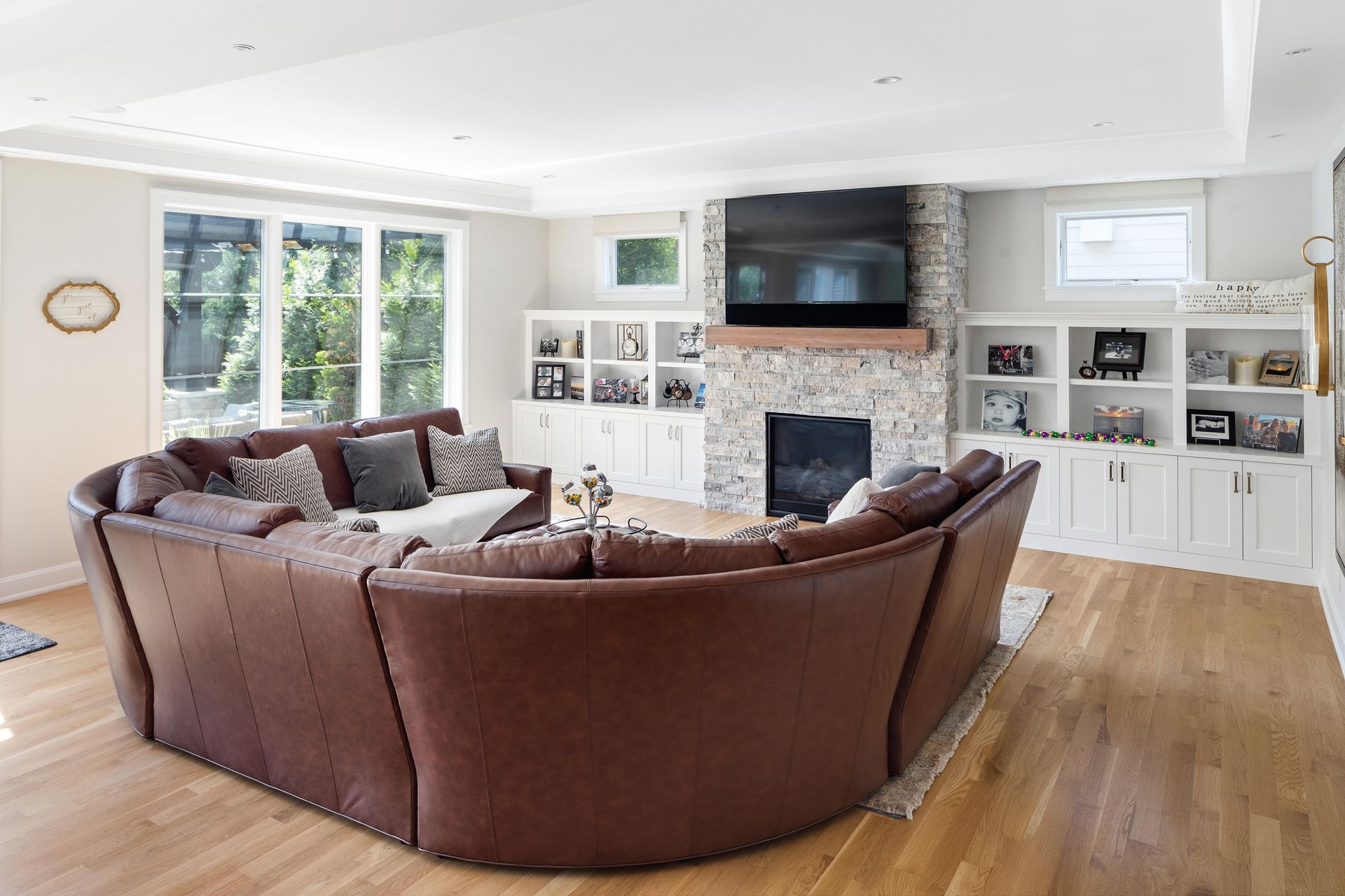 Living room with a large brown sectional sofa, fireplace, built-in shelves, and hardwood floors.