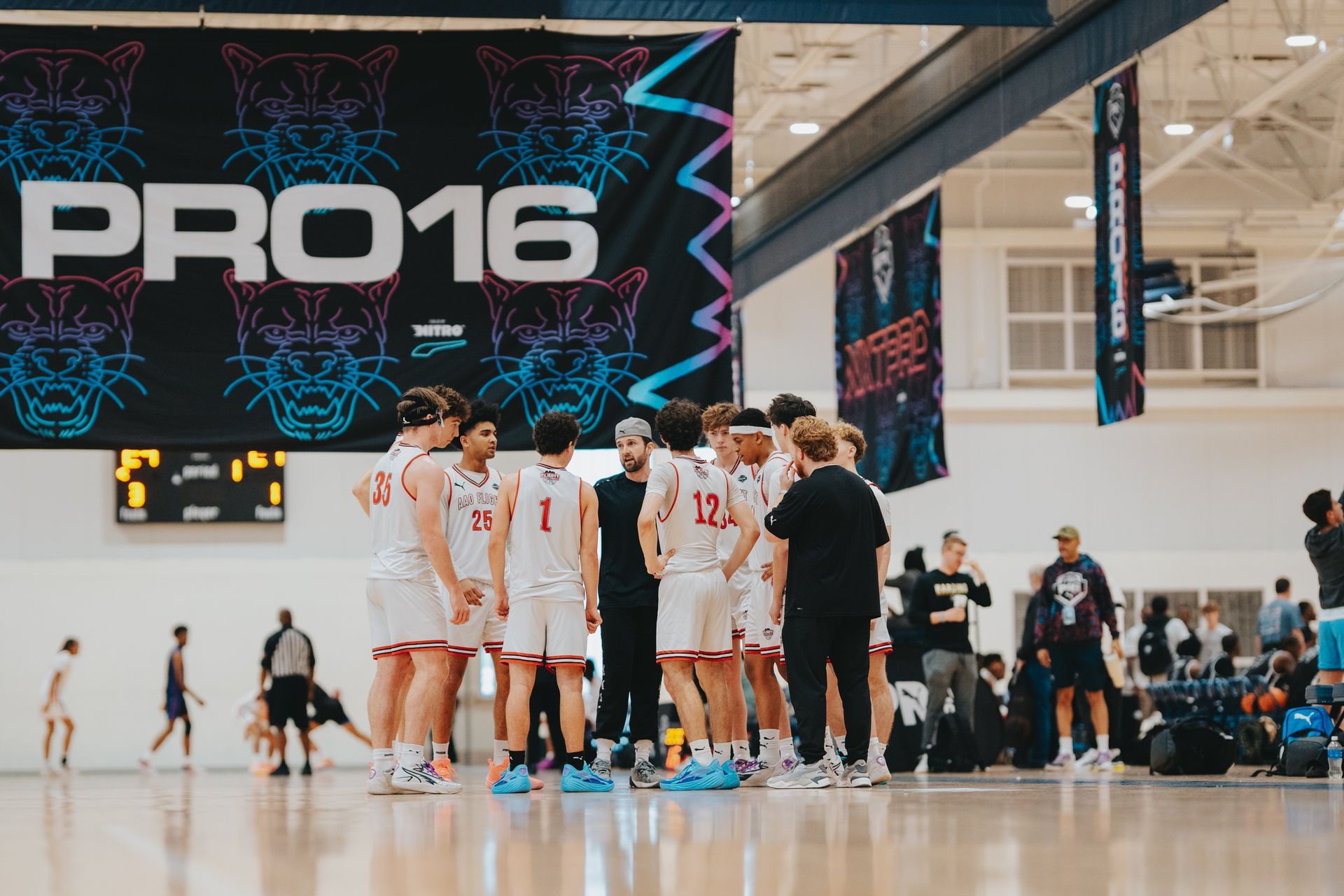 Basketball player, number 34, in black uniform, looks forward in a gym, others blurred in the background.