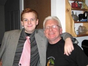 A man and a boy are posing for a picture and the boy is wearing a pink tie