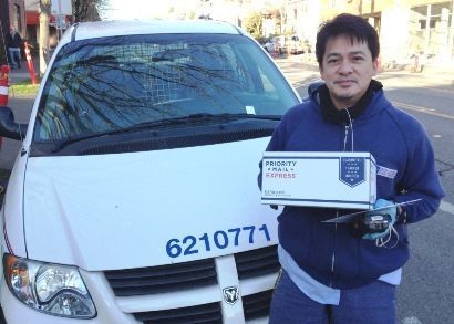 A man holding a box in front of a white van with the number 6210771 on it