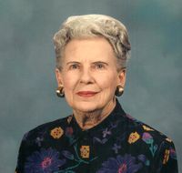 An elderly woman wearing a floral jacket and earrings is posing for a picture.