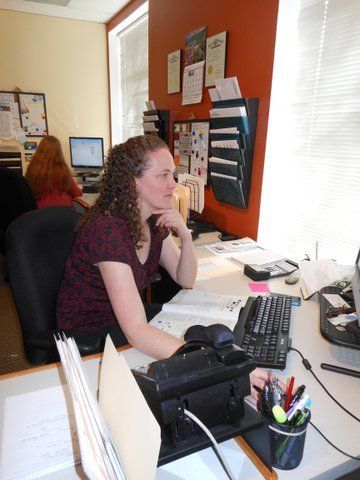 A woman sits at a desk in front of a computer