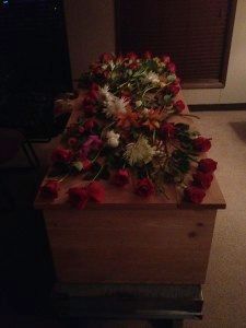 A wooden coffin with flowers on top of it in a dark room.