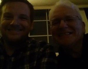 Two men are smiling for a picture together in a dark room.