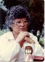 An elderly woman is sitting at a table with a cup of coffee.