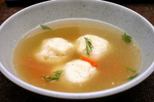 A bowl of soup with dumplings and carrots in it.