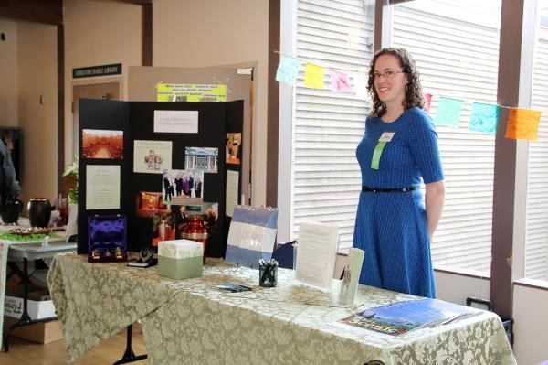A woman in a blue dress is standing in front of a table.