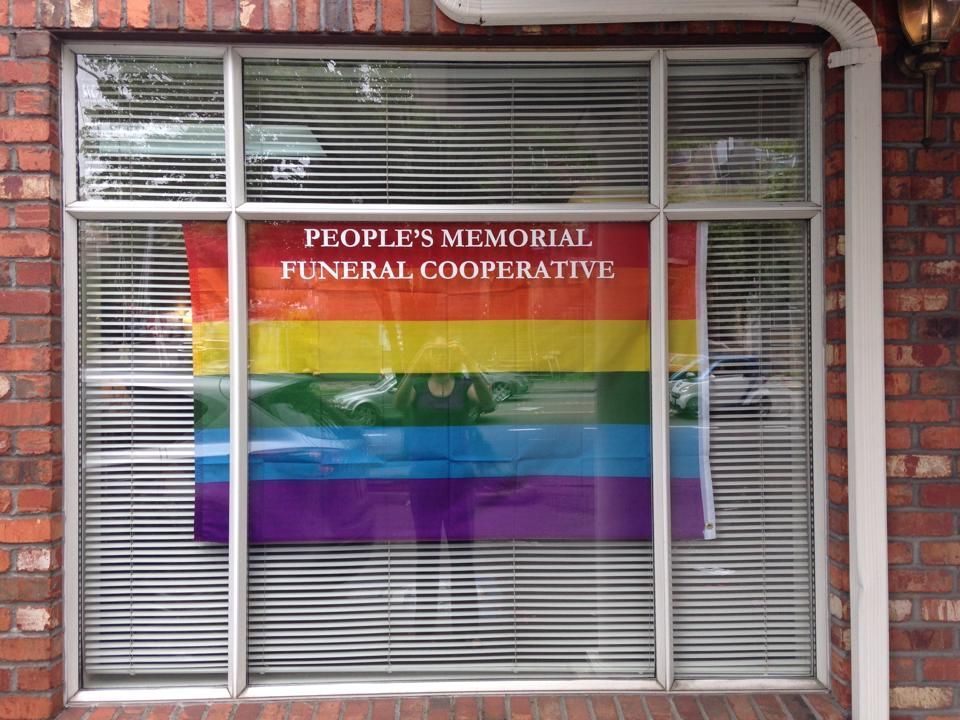A window with a rainbow flag on it that says people 's memorial funeral cooperative