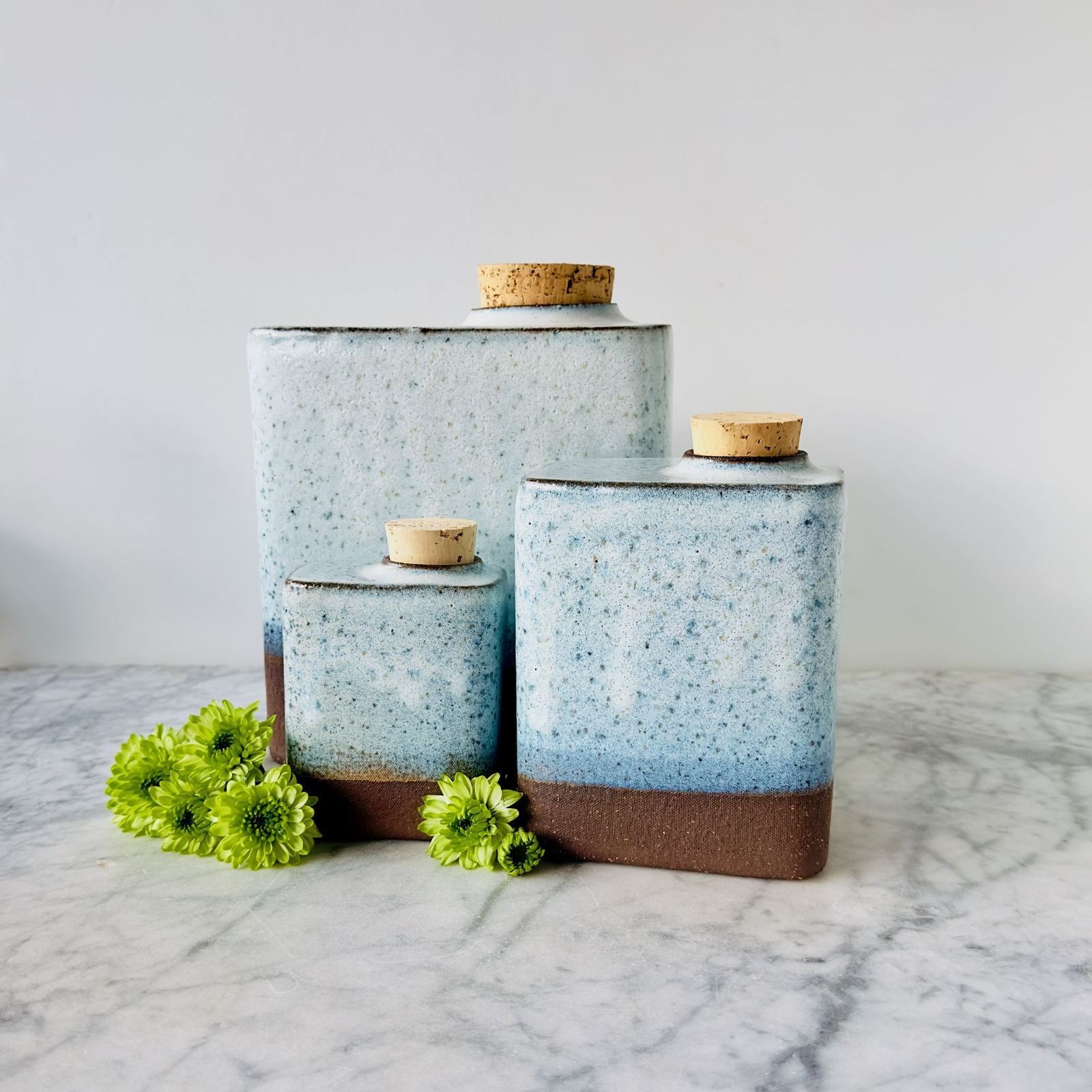 Three ceramic jars with corks are stacked on top of each other