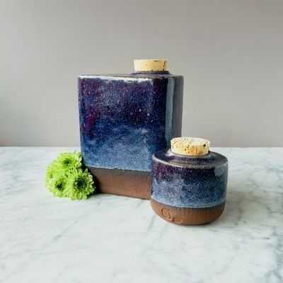 Two blue vases with corks are sitting on a marble table.