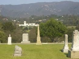 A cemetery with a church in the background and mountains in the background.