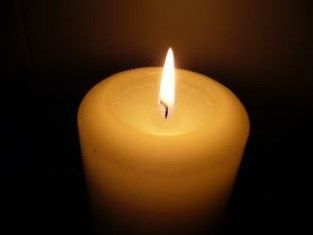 A close up of a lit candle in the dark.