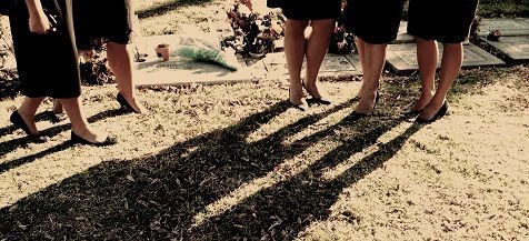 A group of women in black dresses are walking on the ground.