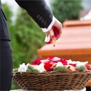 A man in a suit is putting flowers in a basket.