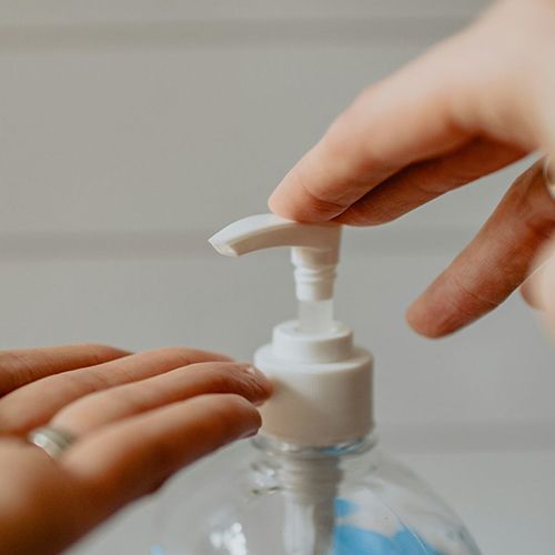 A person is pouring hand sanitizer into a bottle.