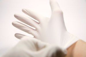 A person is putting on a pair of white gloves.