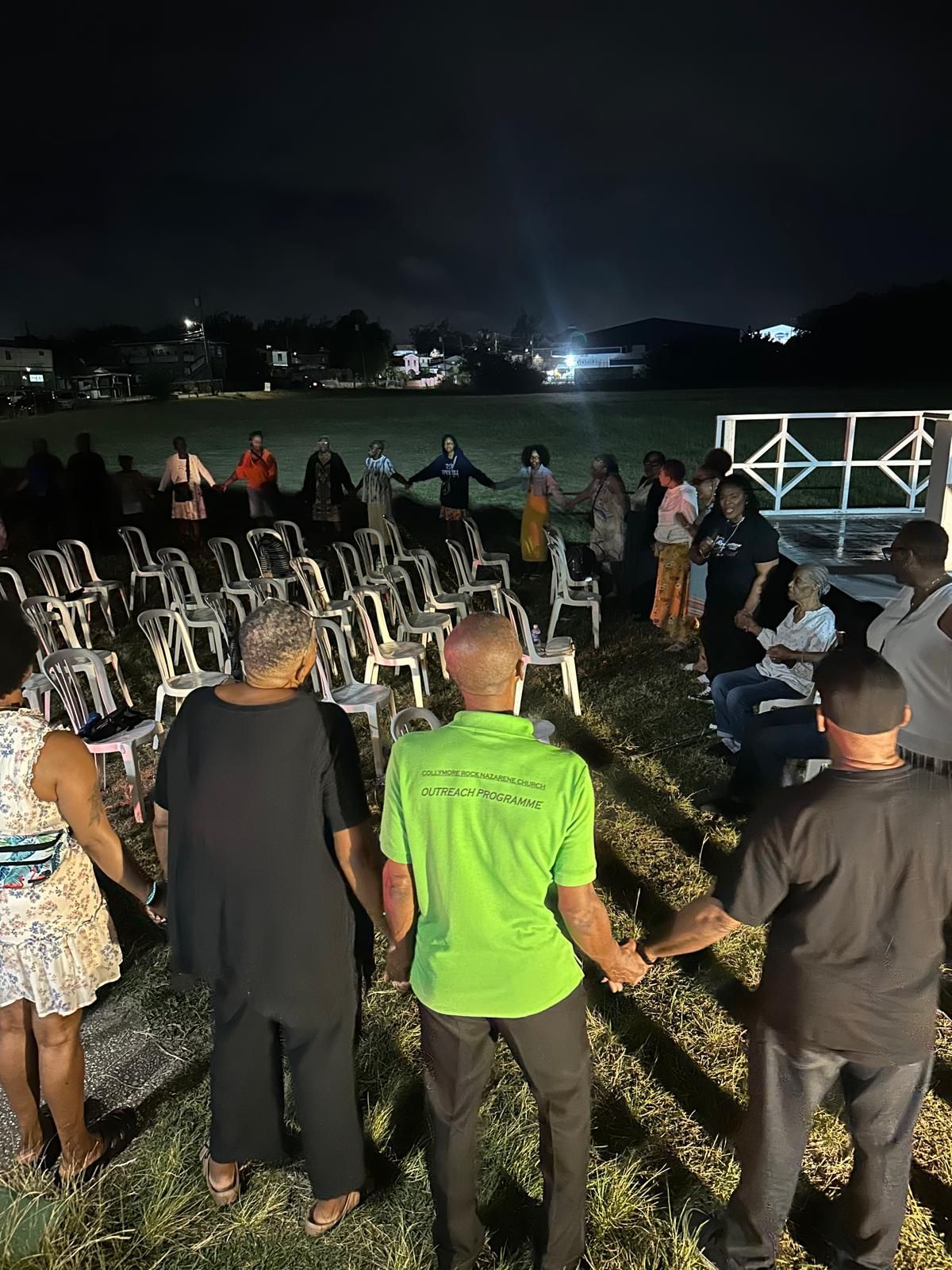 A group of people are standing in a field at night holding hands.
