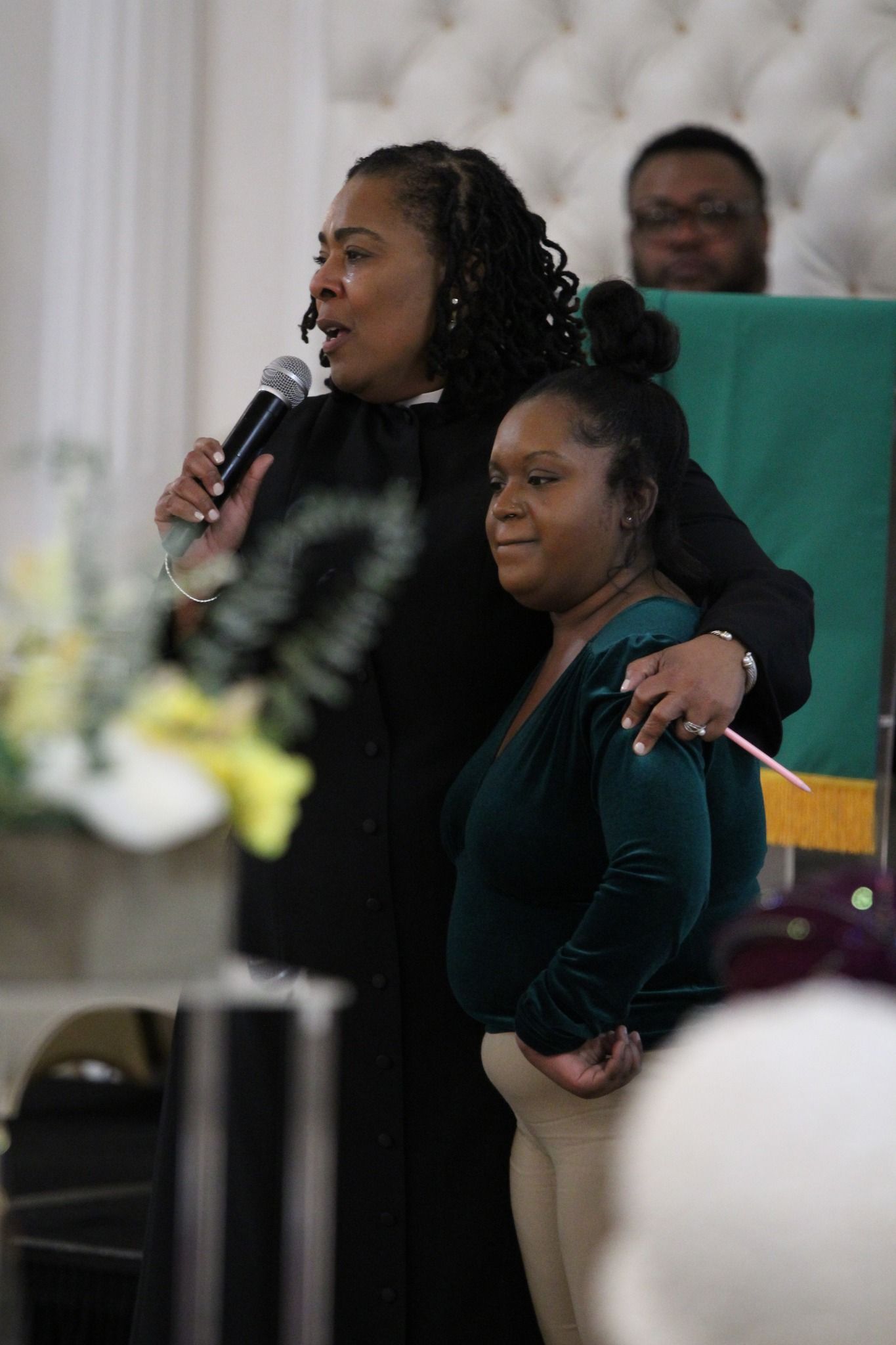 A woman is holding a microphone while standing next to another woman.