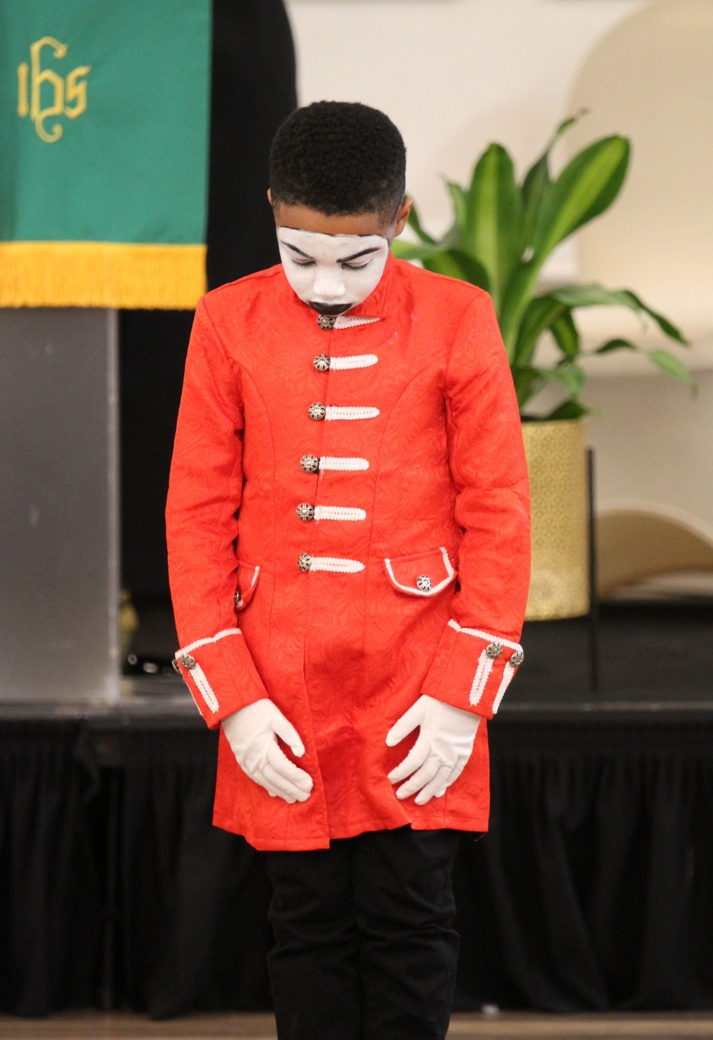 A boy wearing a red coat and white face paint