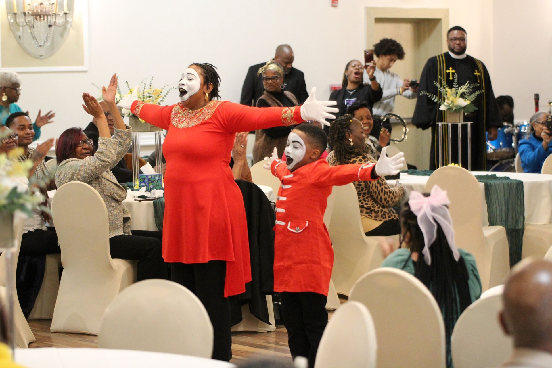 A woman and a child are dancing in front of a crowd at a party.