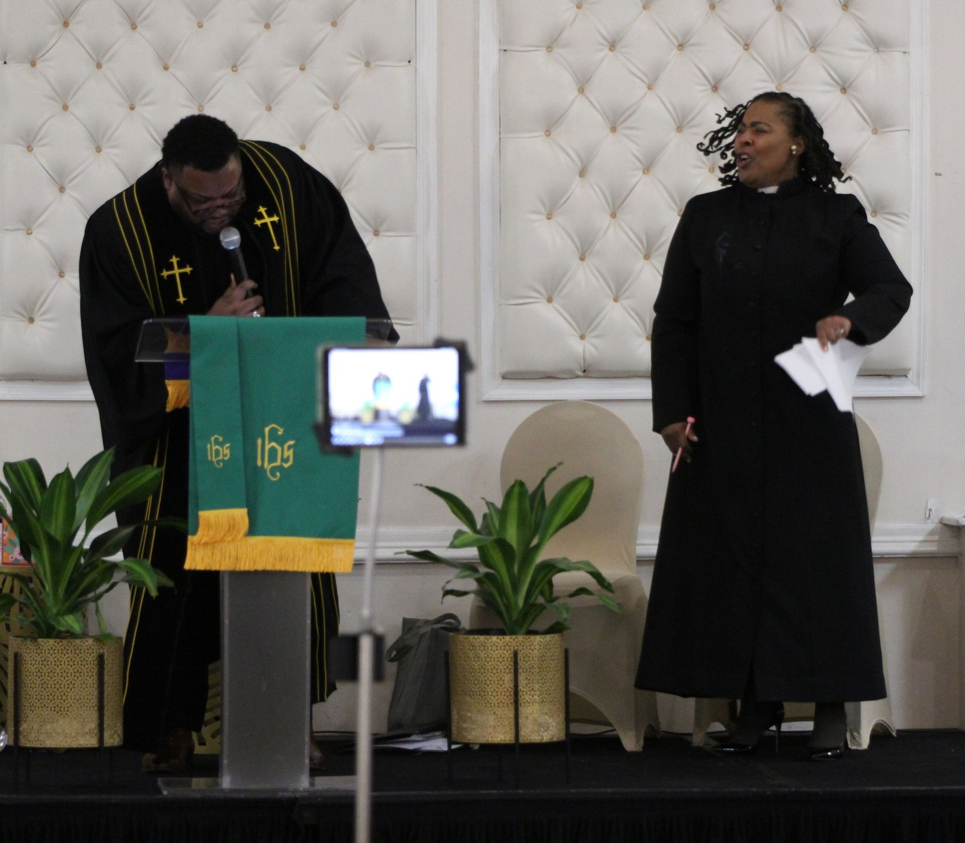 A man stands at a podium while a woman stands behind him