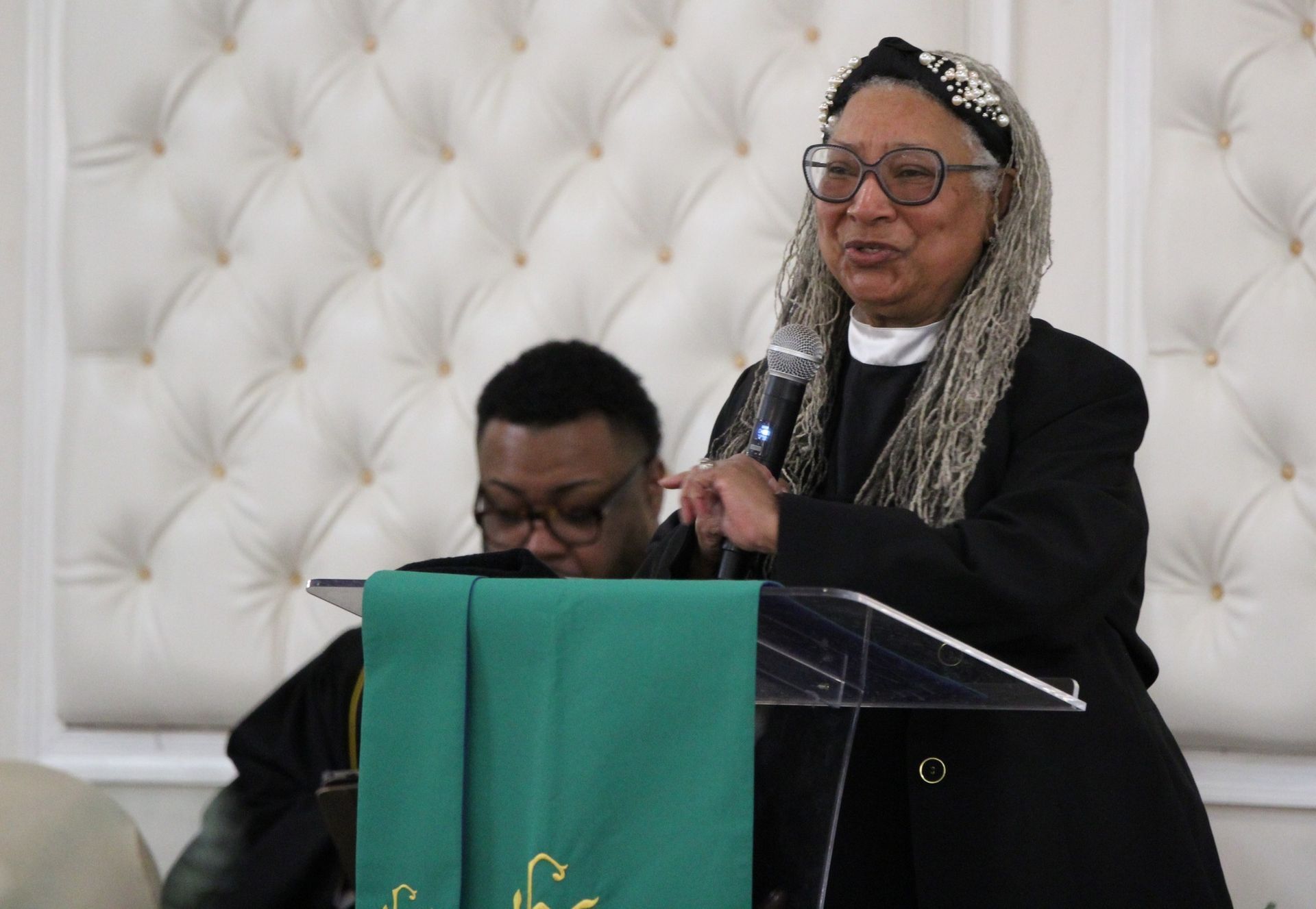 A woman is standing at a podium speaking into a microphone