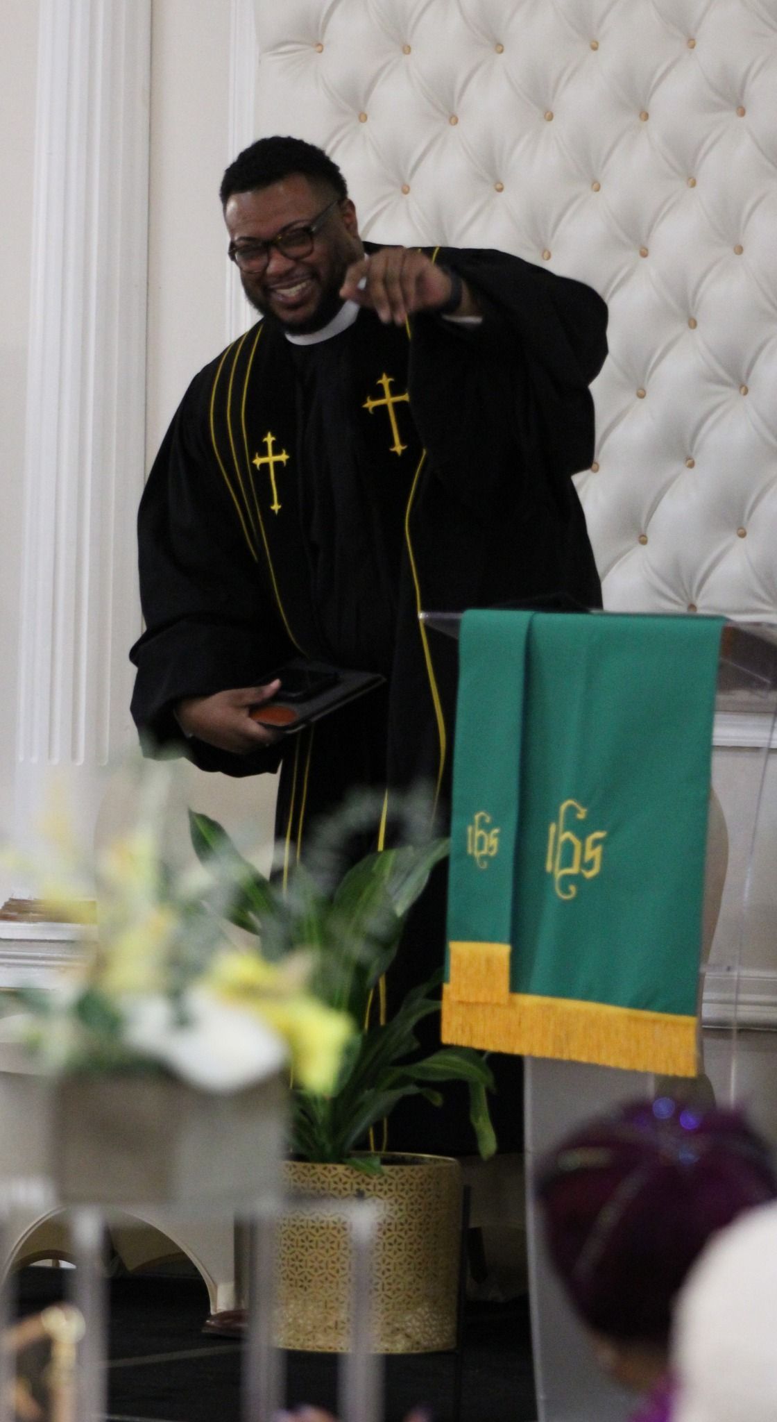 A man in a black robe is standing at a podium giving a speech.