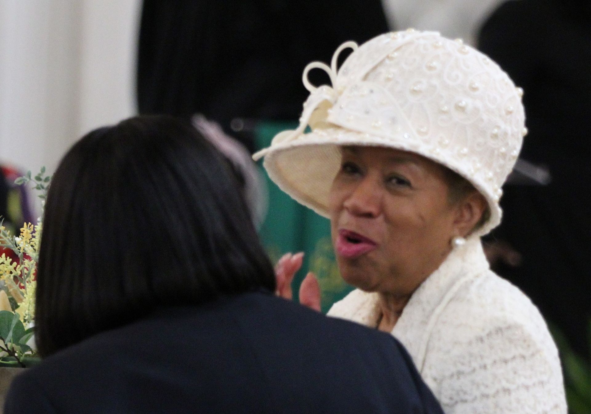 A woman wearing a white hat is talking to another woman