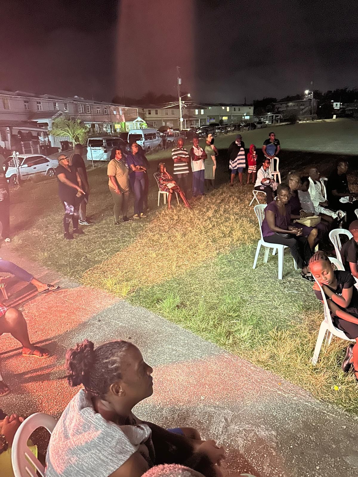 A group of people are sitting in chairs in a park at night.