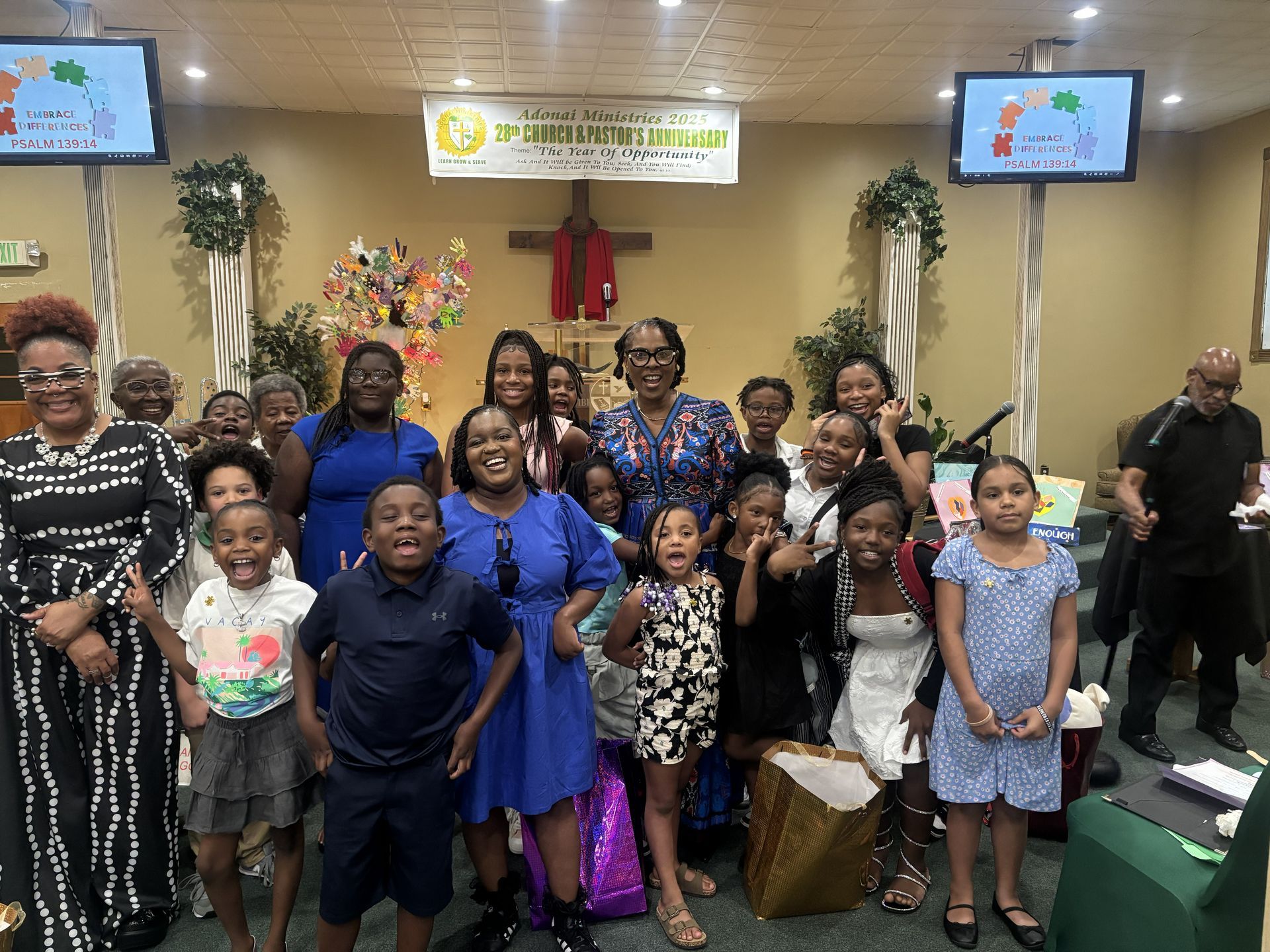 Group of people, mostly children, posing for a photo inside a church, smiling.