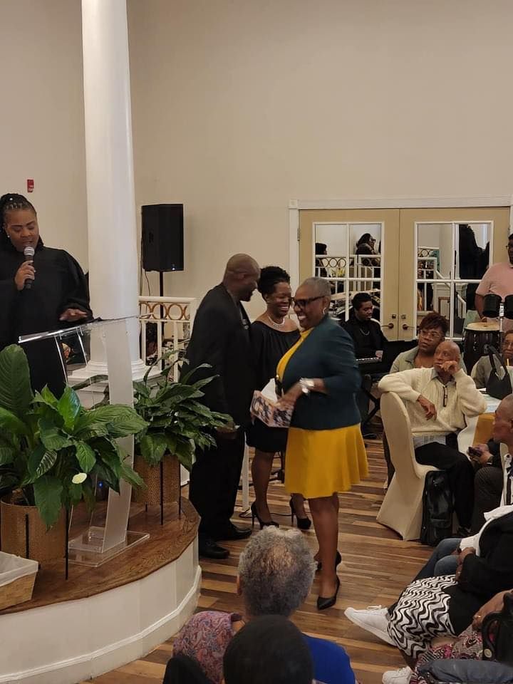A woman in a yellow skirt is standing in front of a crowd of people.
