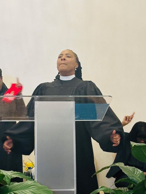A woman in a black robe is standing at a podium