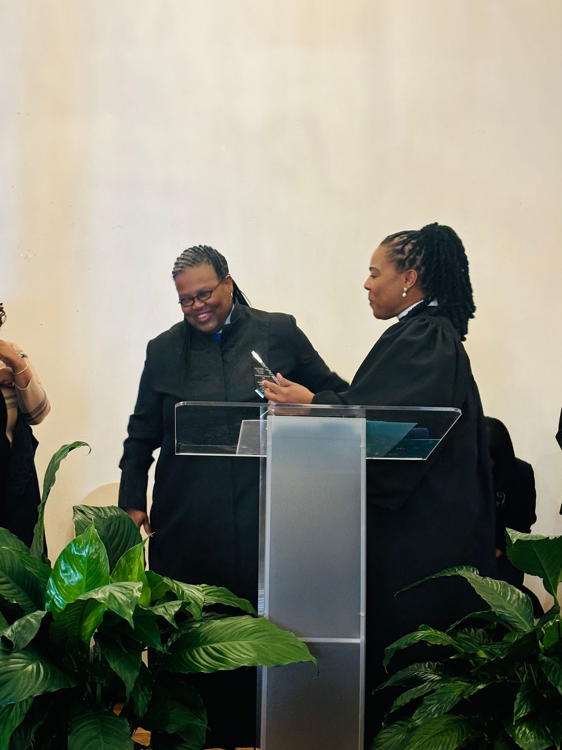 Two women are standing at a podium talking to each other.