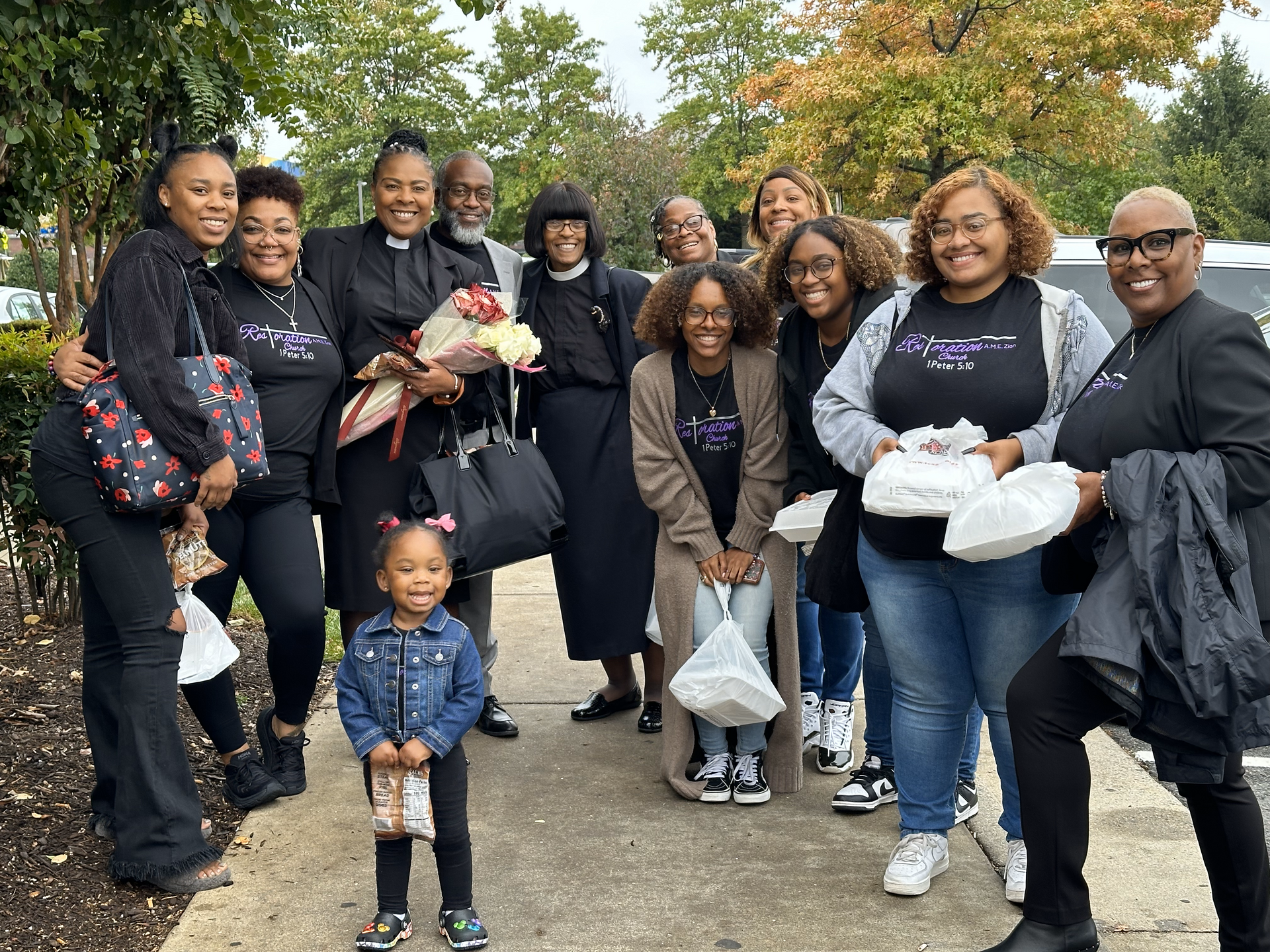A group of people are posing for a picture on a sidewalk.