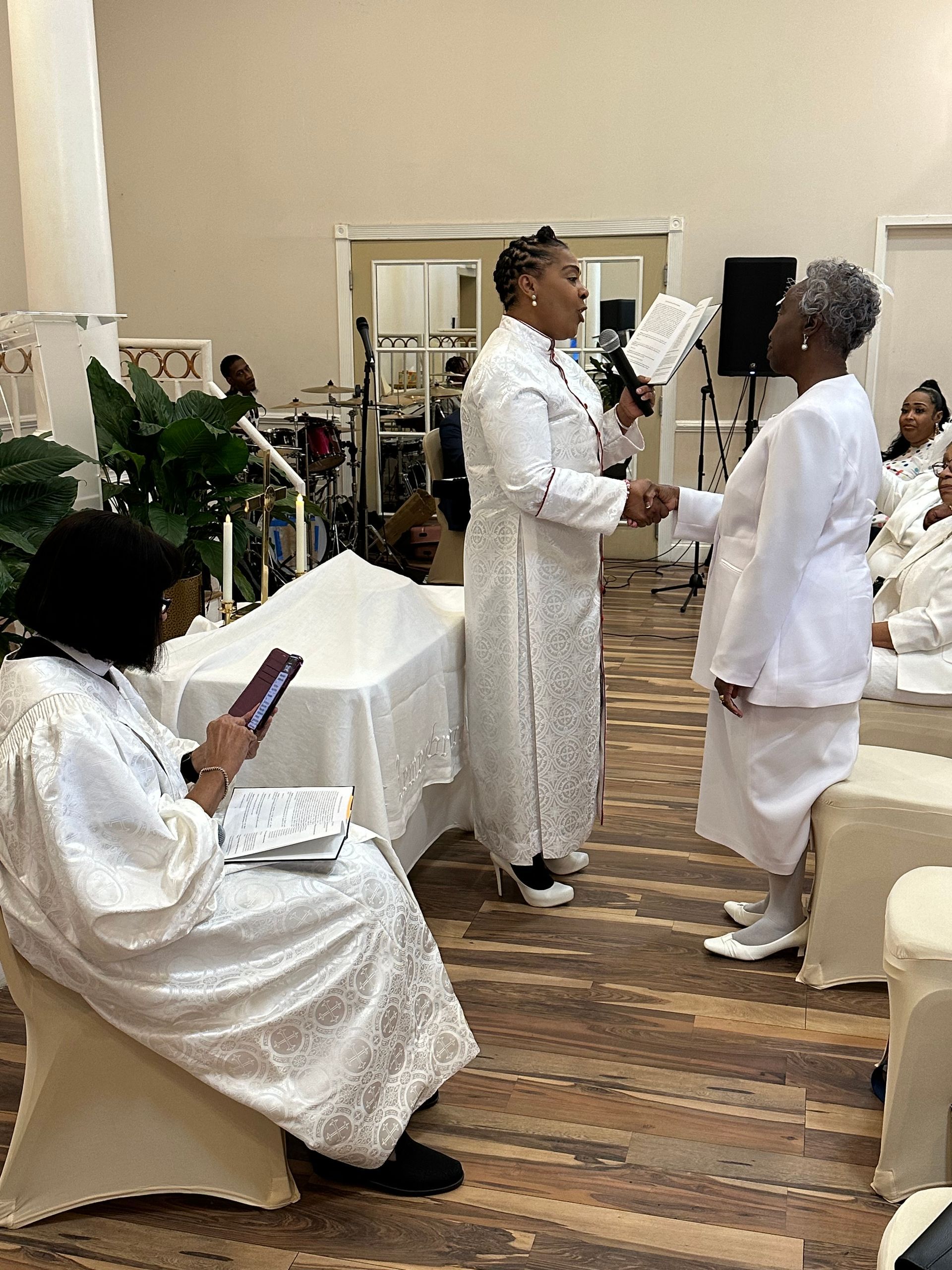 A group of women in white robes are standing in a room.