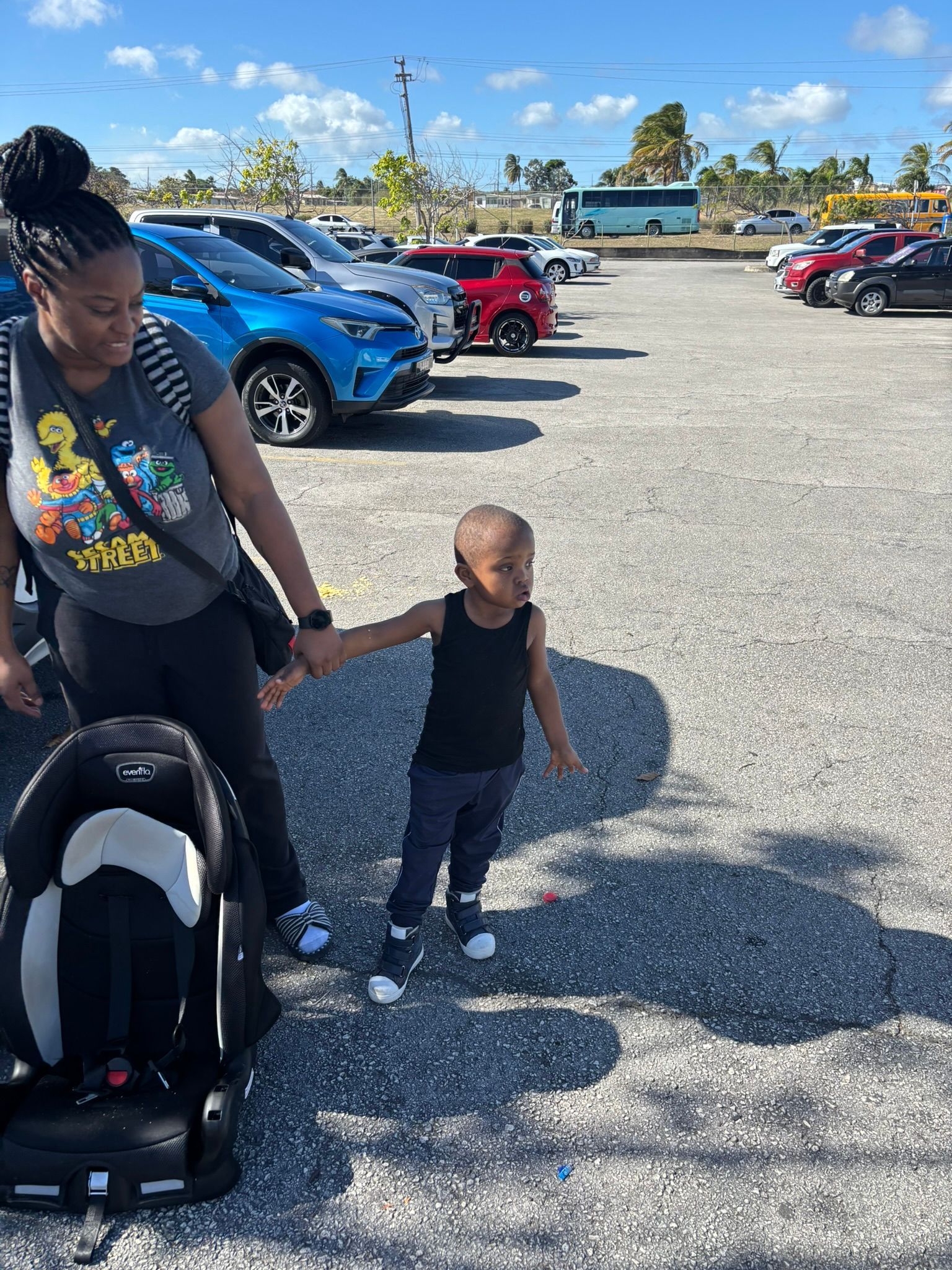 A woman and a child are holding hands in a parking lot.