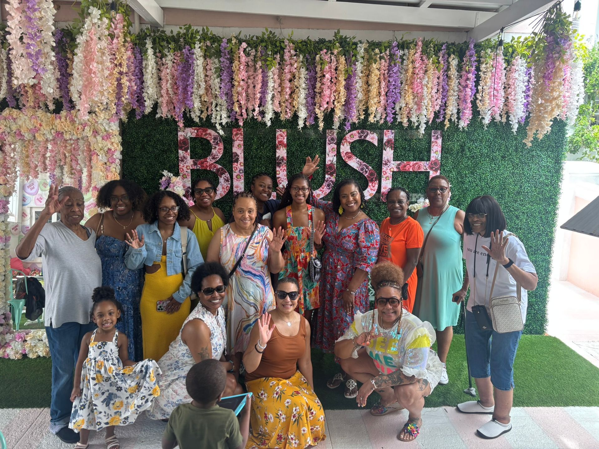 A group of people are posing for a picture in front of a sign that says blush.