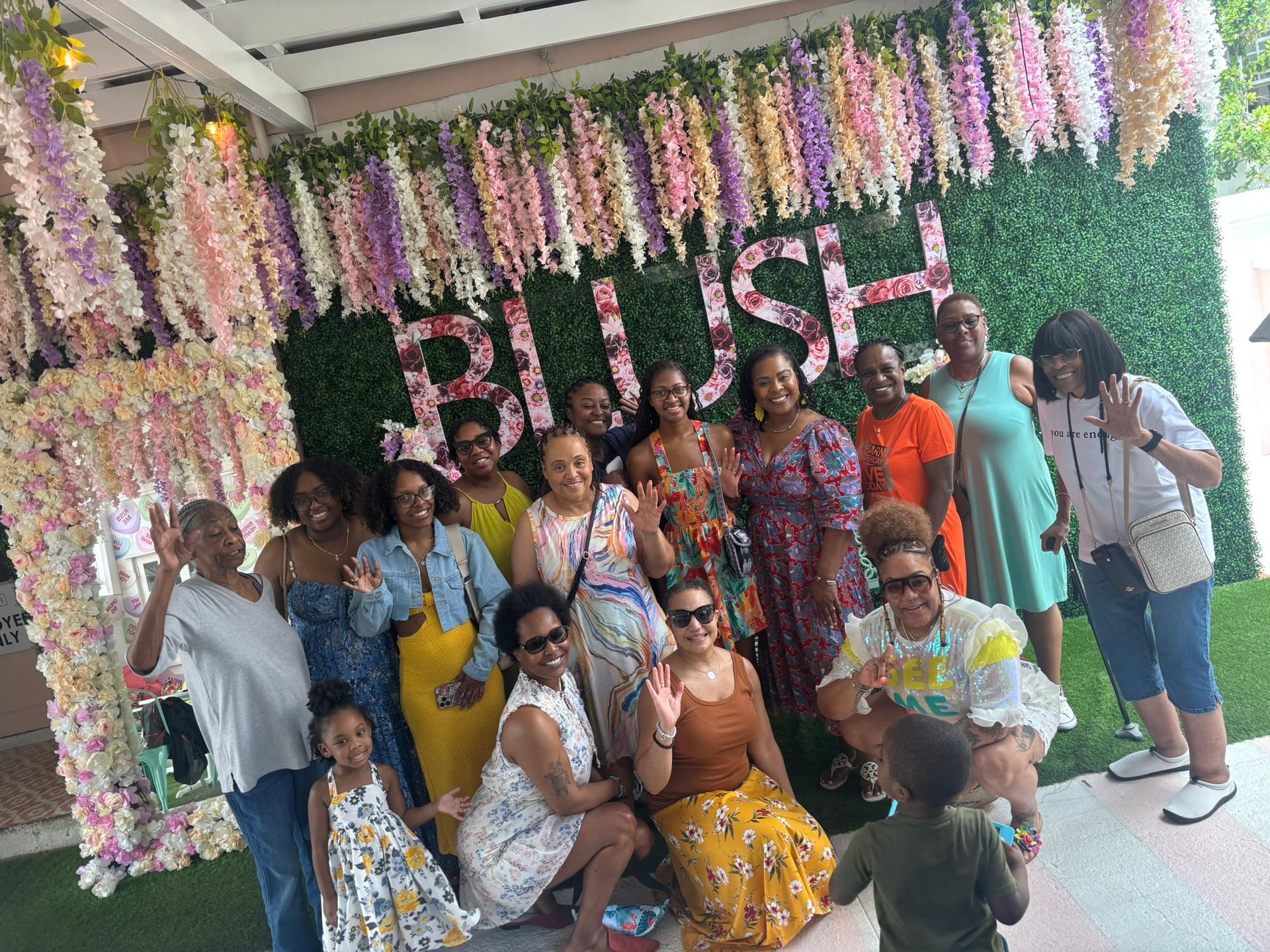 A group of women are posing for a picture in front of a flower wall.