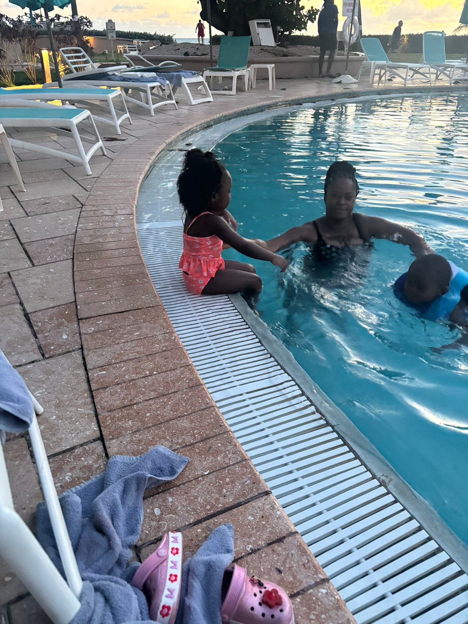 A woman and two children are playing in a swimming pool.