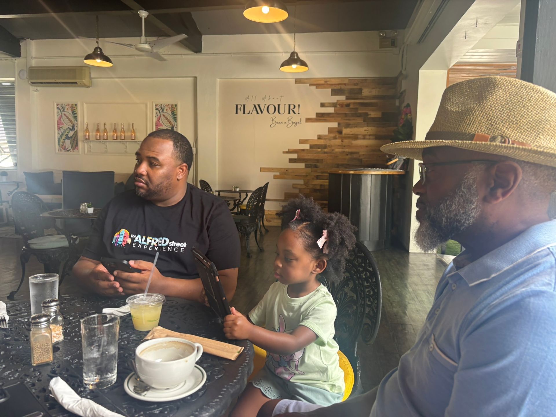 Two men and a little girl are sitting at a table in a restaurant.