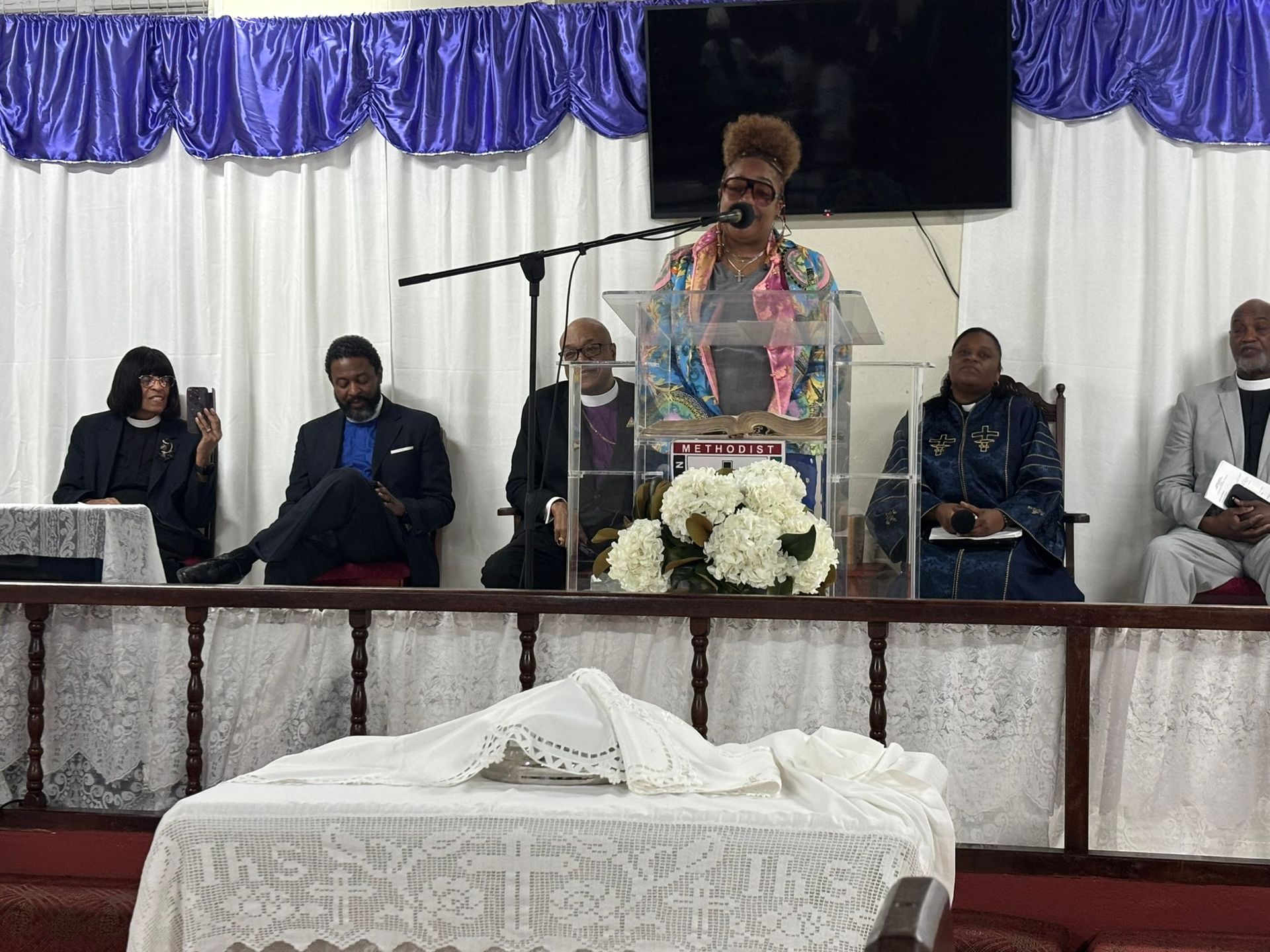 A woman is giving a speech in front of a microphone in a church.
