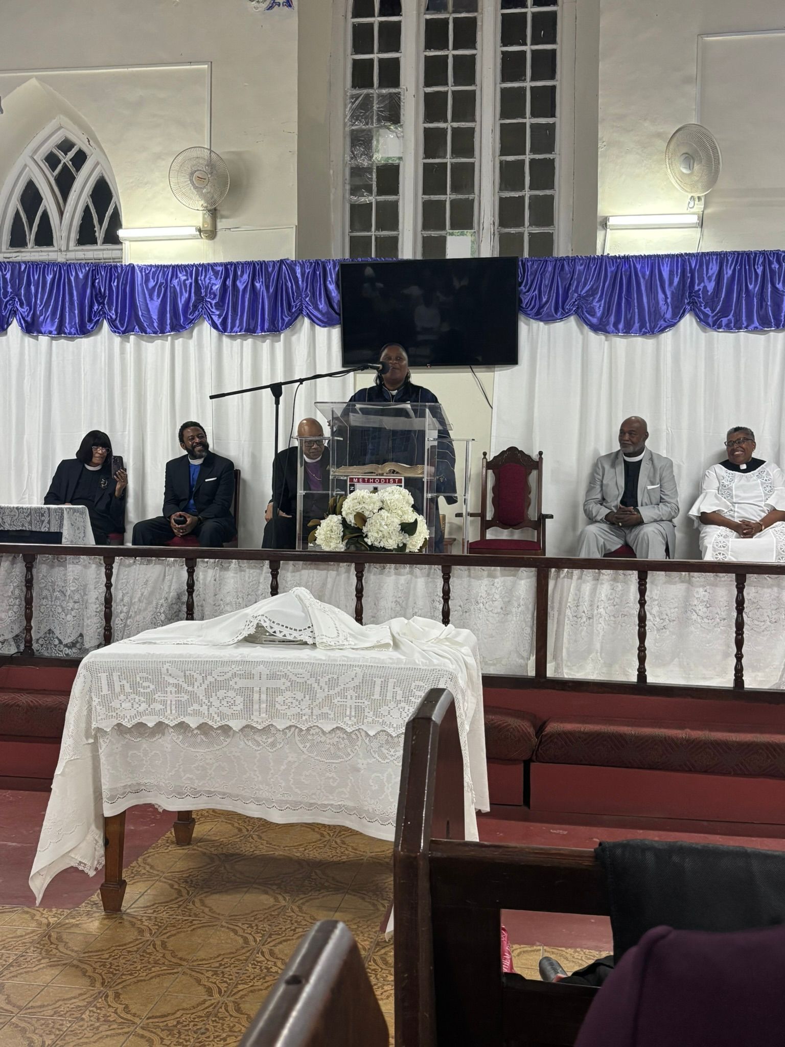 A man is standing at a podium in front of a group of people in a church.