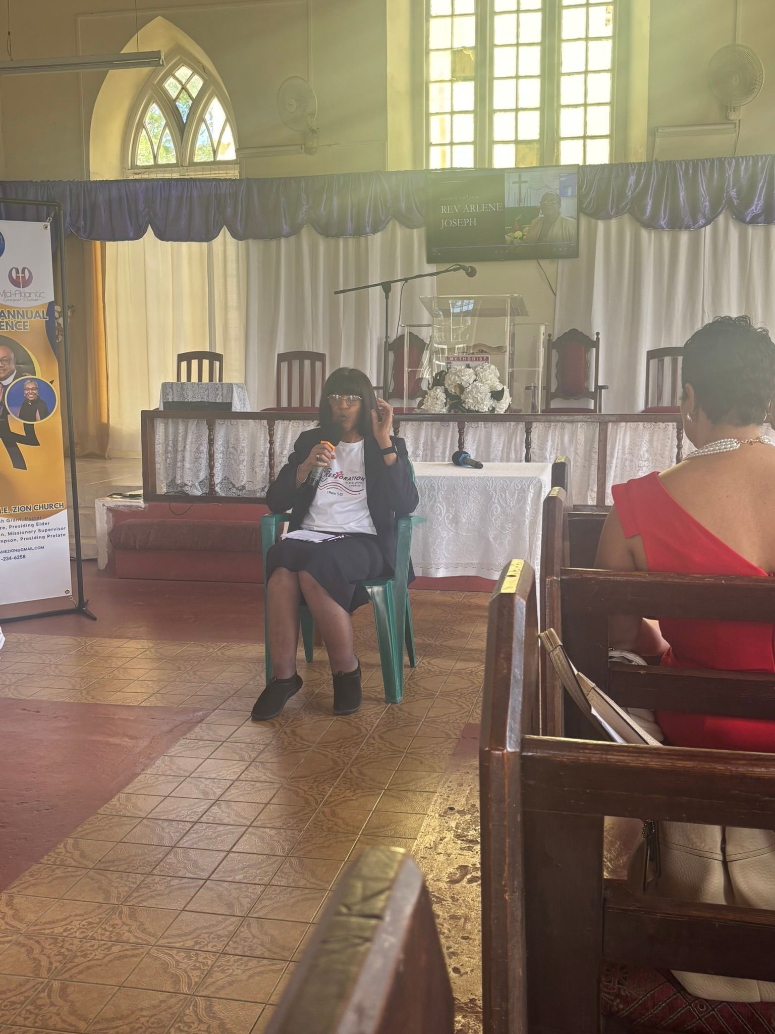 A woman in a red dress is sitting in a chair in a church.
