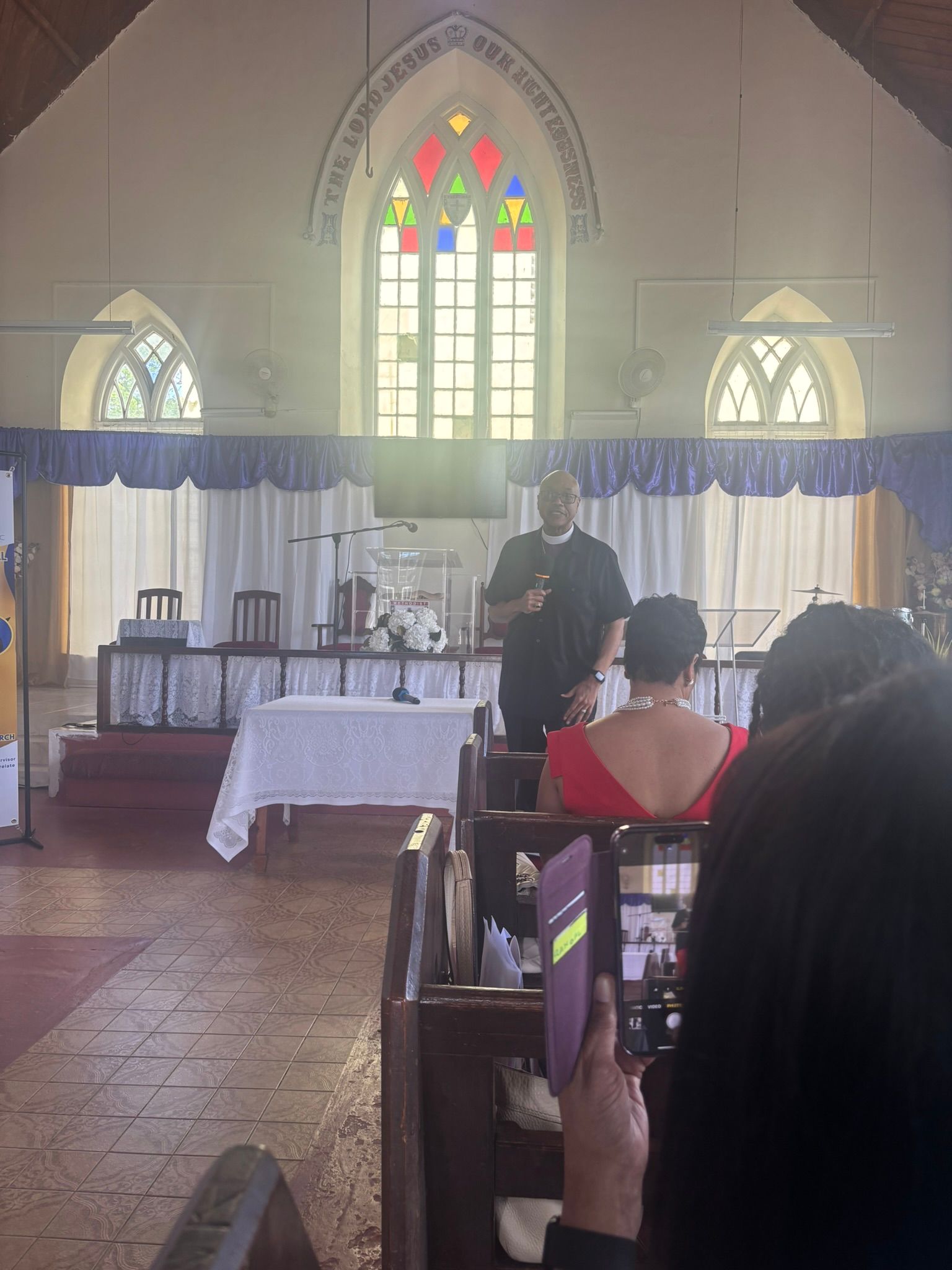 A man is giving a sermon in a church with people sitting in the pews.