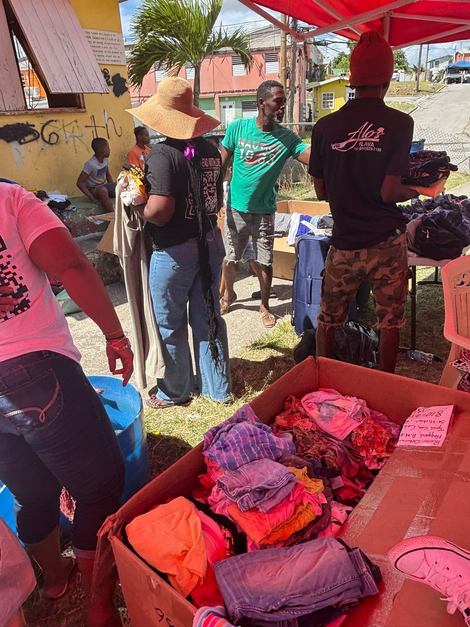 A group of people are standing around a box of clothes.