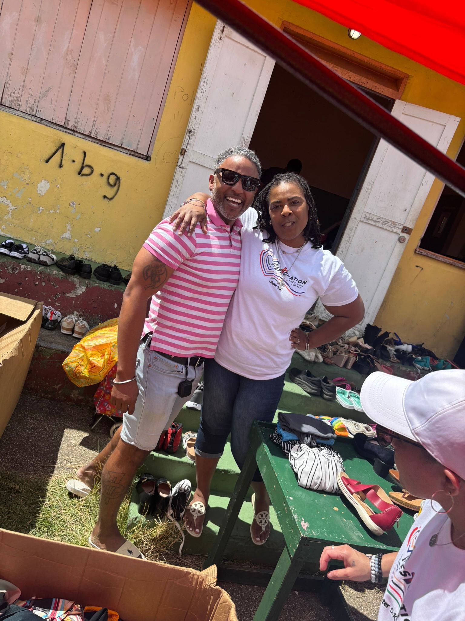Two women are posing for a picture in front of a yellow building.