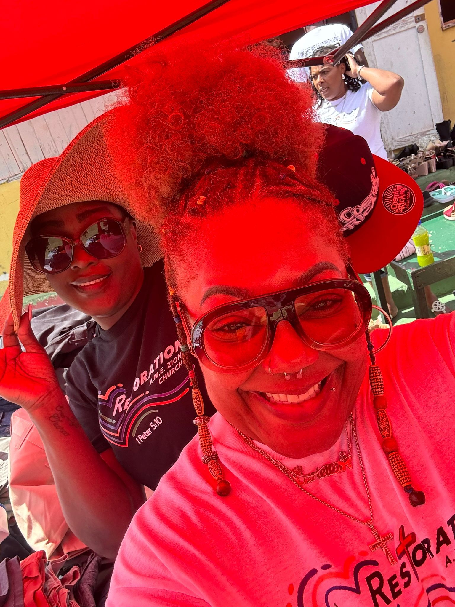 A woman wearing sunglasses and a hat is standing next to another woman wearing sunglasses and a hat.