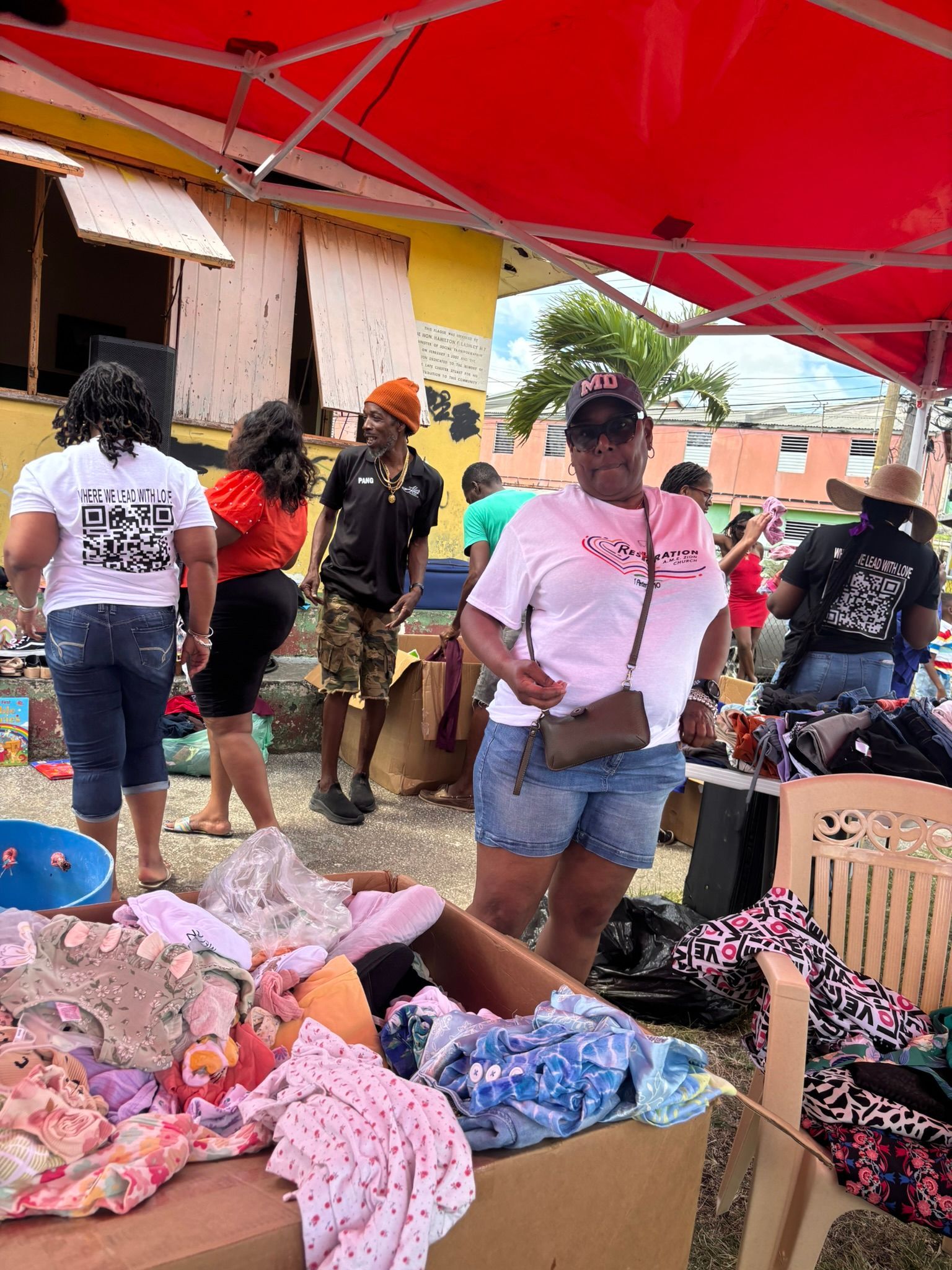 A woman is standing in front of a table full of clothes at a flea market.