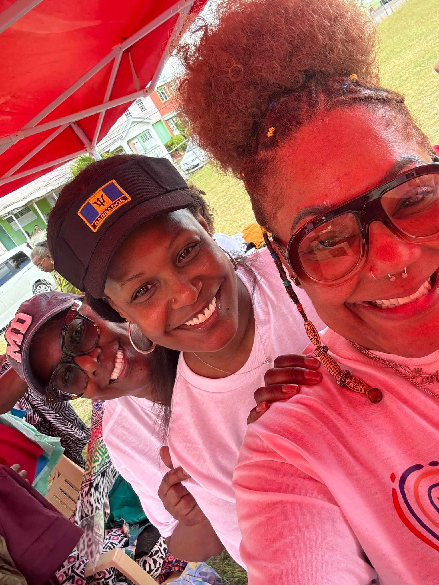 Three women are posing for a picture in front of a red tent.