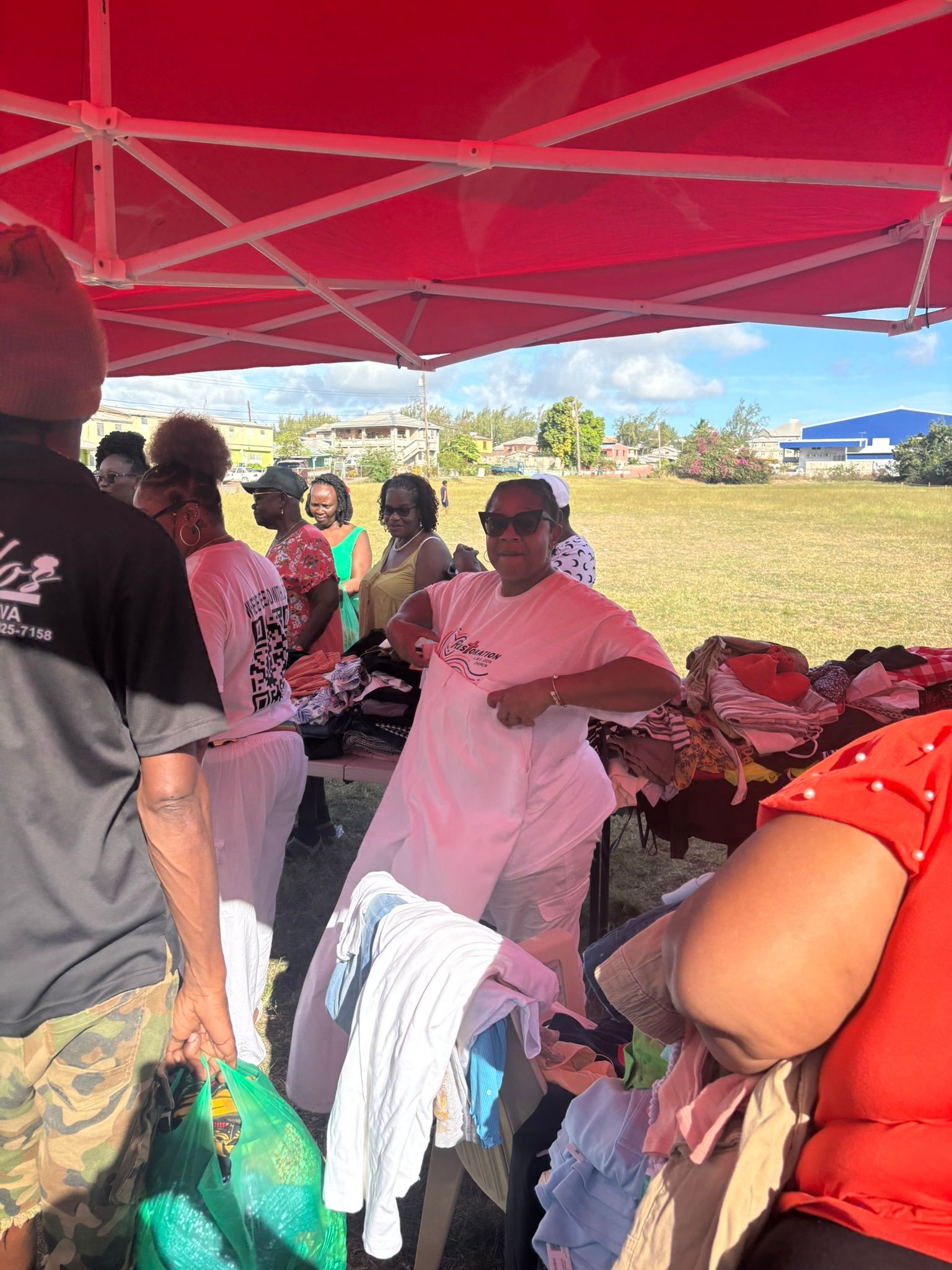 A group of people are standing under a red tent.